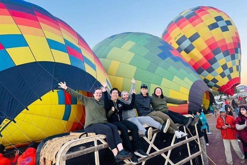 Un grupo de personas sentadas en una plataforma con coloridos globos aerostáticos al fondo. 3