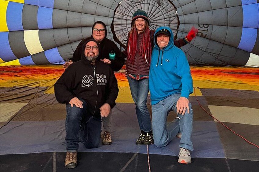 A group of people posing in front of a hot air balloon. 3