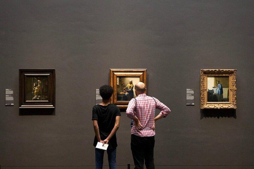 Two people examining paintings in an art gallery. 1