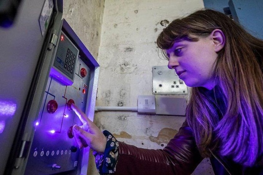 En person som använder en kontrollpanel med upplysta knappar och ett numeriskt tangentbord. 2