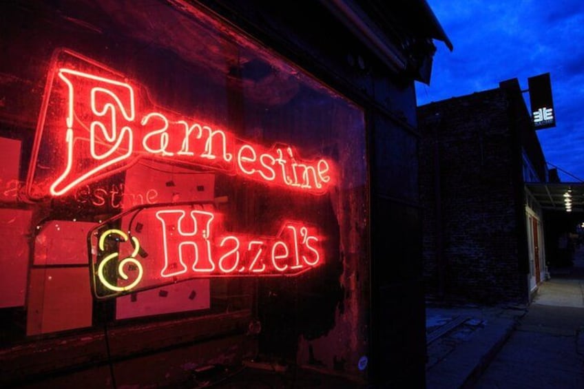 A neon sign for 'Earnestine & Hazels' on a building at night. 4
