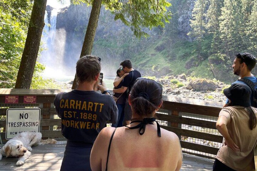 A group of people taking photos of a waterfall. 2
