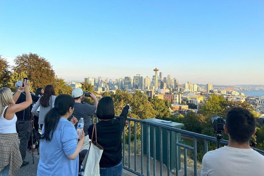A group of people taking photos of a city skyline with a prominent tower. 3