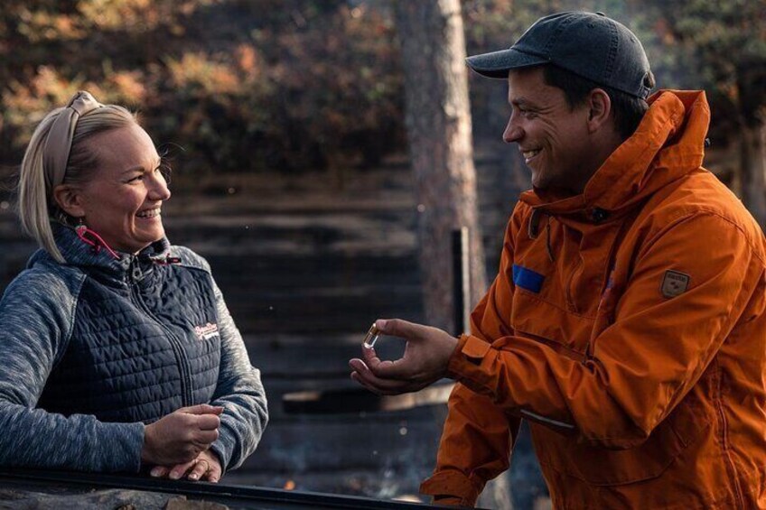 Two people in outdoor gear, one in a dark jacket and the other in an orange jacket, standing near a vehicle. 3