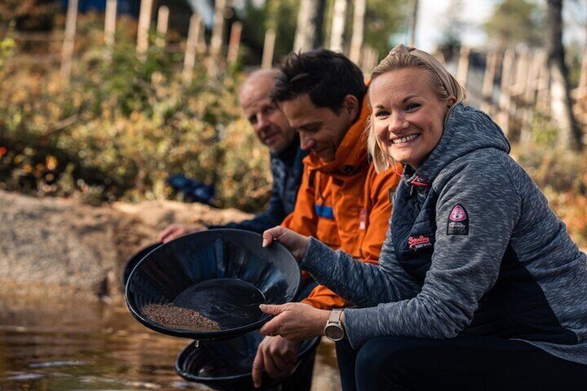 Two people sitting by a river, one holding a black pan. 1