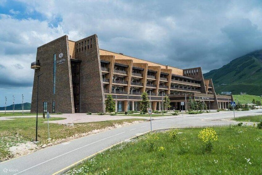 A modern building with a unique architectural design, surrounded by a grassy area and a road. 2