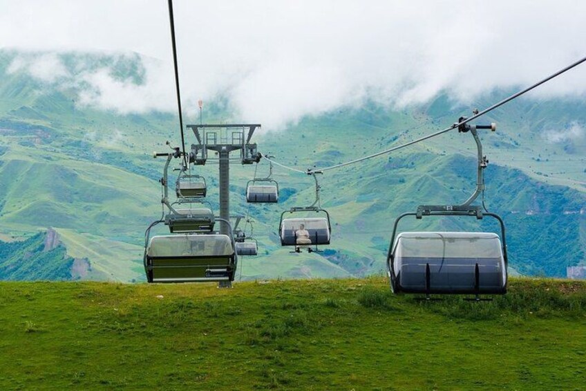 A cable car system in a mountainous area with lush green hills and misty clouds in the background. 5