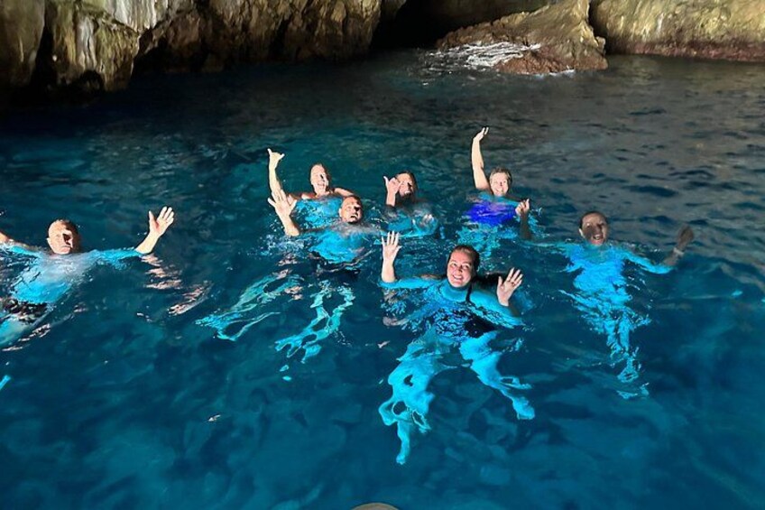 Menschen schwimmen in einem Pool mit klarem, blauem Wasser und Felsformationen im Hintergrund. 3