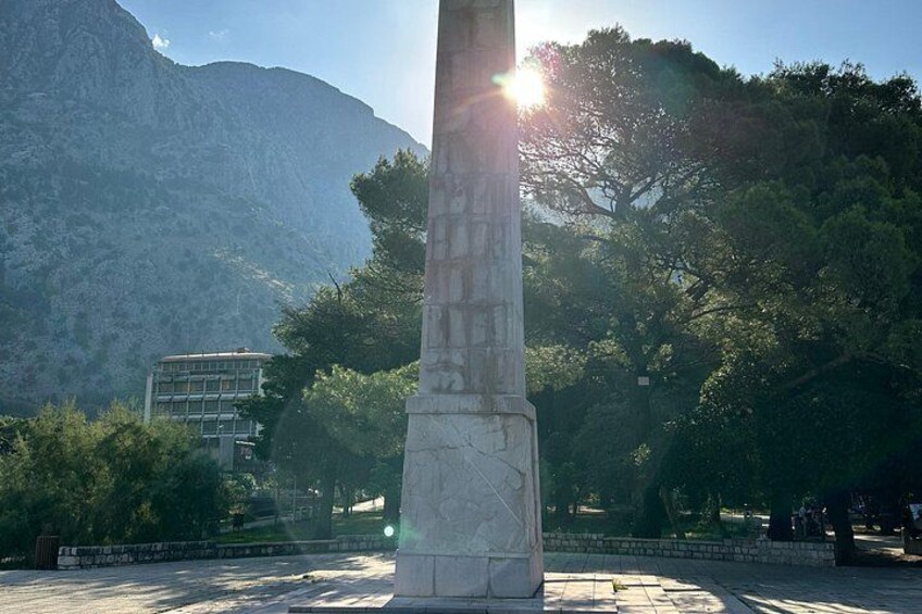 Ein hohes Steins Denkmal in einem Park mit Bäumen und Bergen im Hintergrund. 5
