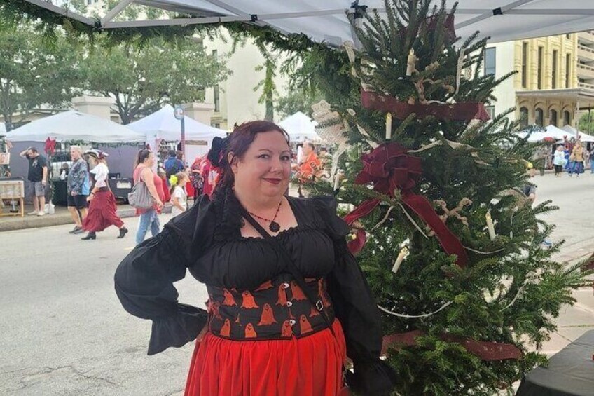 Una persona in costume storico in piedi accanto a un albero di Natale addobbato. 2