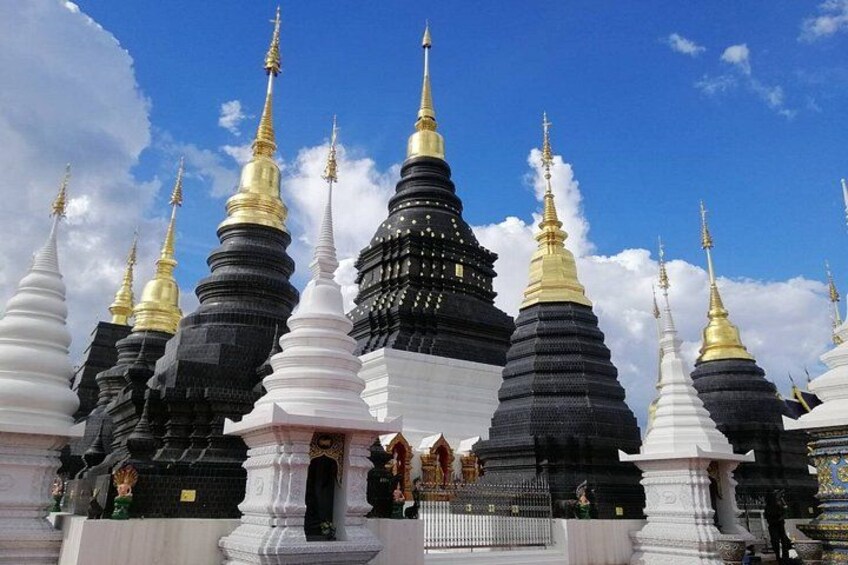A collection of pagodas with golden spires, surrounded by a fence. 2
