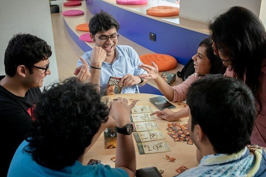 A group of people playing a card game at a table with cards and chips. 2
