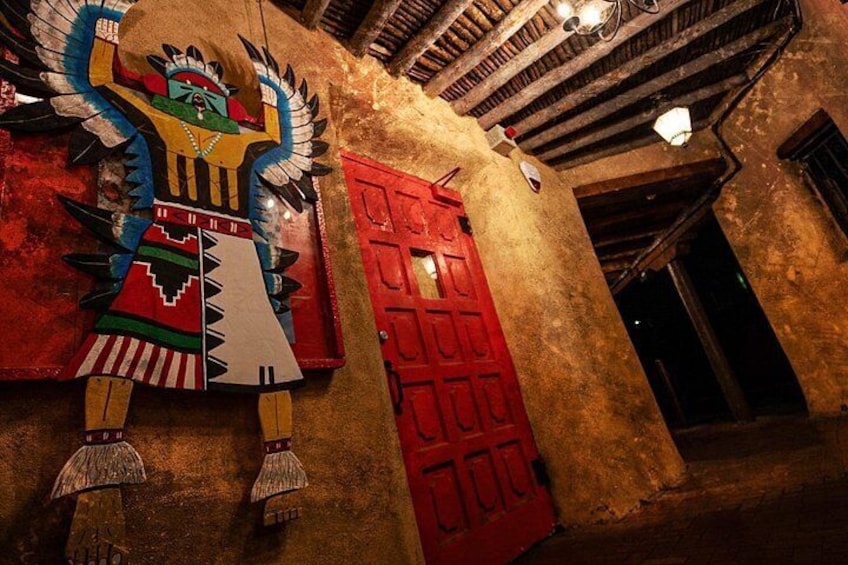 Un mural con la imagen de una figura alada, una puerta roja y un techo rústico. 3