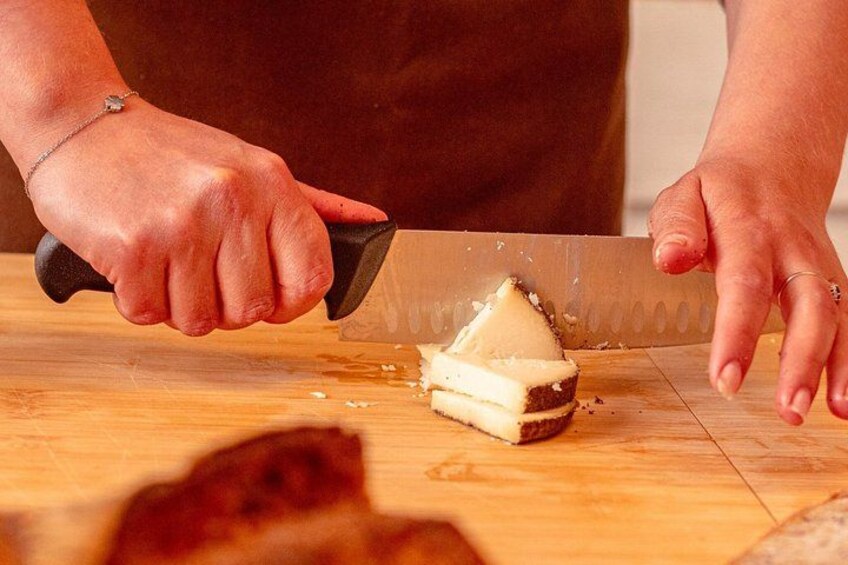 A person cutting cheese on a wooden cutting board. 1