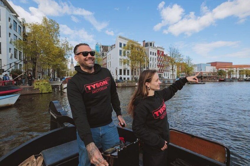 Dos personas en un bote en un canal, con edificios al fondo. 3