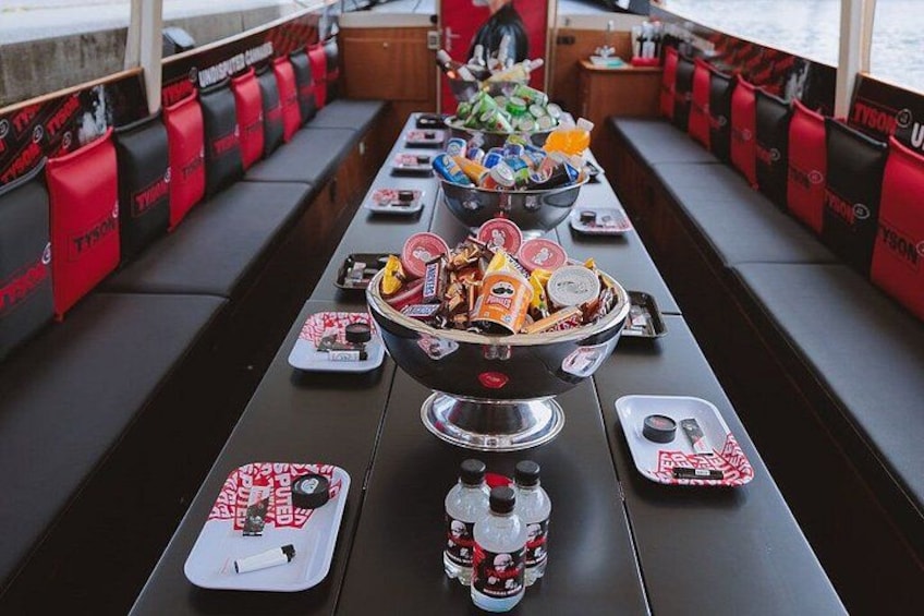 A boat deck with seating and a table set with food and drinks. 2
