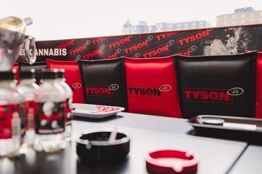 Et bord med røde og sorte tasker mærket 'TYSON', en cannabisflaske og en lighter. 4
