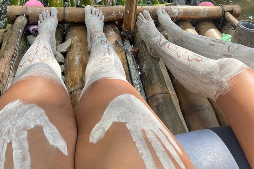 A person lying on a bamboo raft with their legs covered in white substance. 2