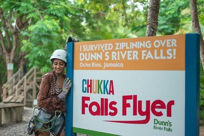 A person leaning on a sign with text about ziplining over Dunn's River Falls in Ocho Rios, Jamaica. 3