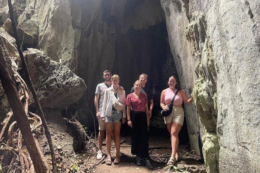 En grupp människor som står vid ingången till en grotta med steniga väggar. 5