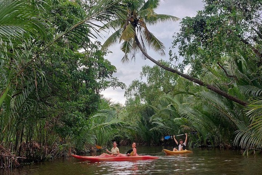 Två personer paddlar kajak på en flod omgiven av tät, tropisk vegetation. 1