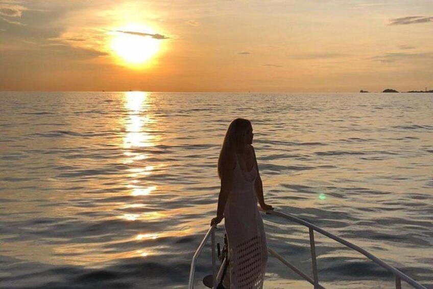 A sunset over a calm sea with a person standing on a boat. 5