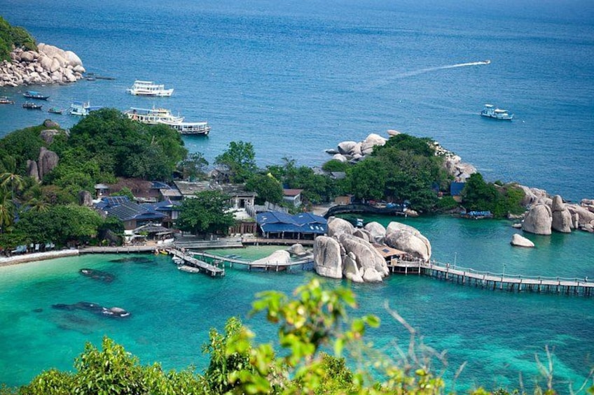 A coastal village with a pier, boats, and large rocks. 4