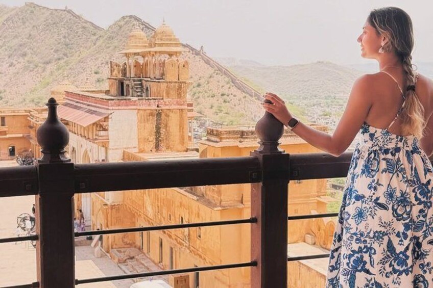 A person standing on a balcony overlooking a historic building with intricate architecture. 5