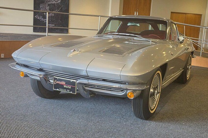 A classic silver convertible car with a black license plate, chrome bumpers, and white-wall tires. 4