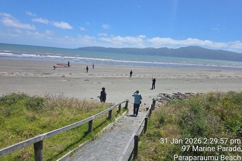 A beach with people walking, a wooden fence, and a clear sky. 3