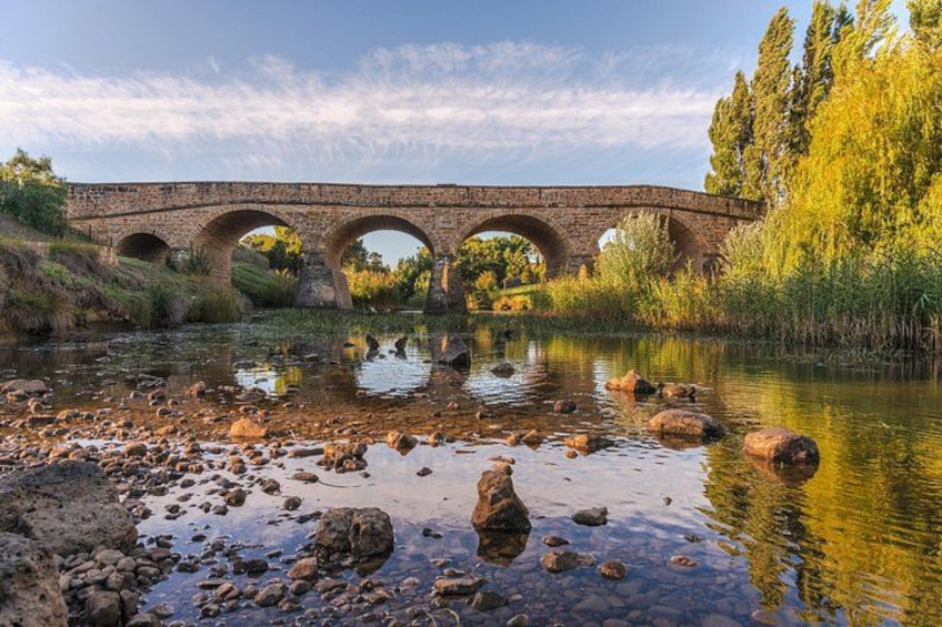 Een stenen brug over een rivier, met rotsen op de voorgrond. 5