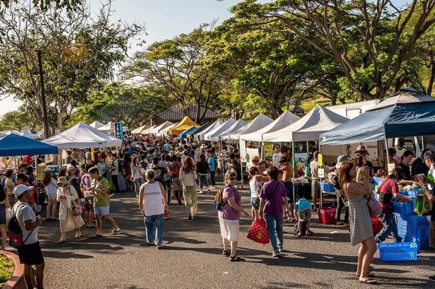 A busy outdoor market with people walking and vendors under tents. 3