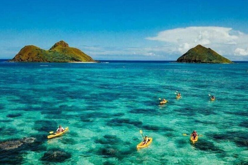 Kayakers on turquoise water with two green islands in the background. 2