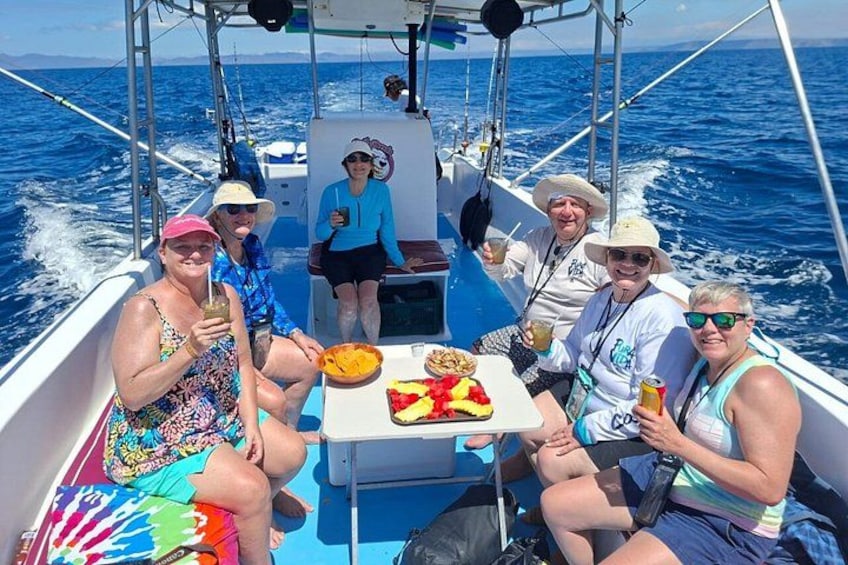 Un grupo de personas en un barco, con una mesa de comida y bebidas. 3