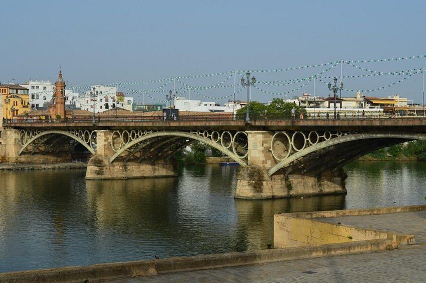 A stone bridge with ornate arches over a river, with buildings and a tower in the background. 5