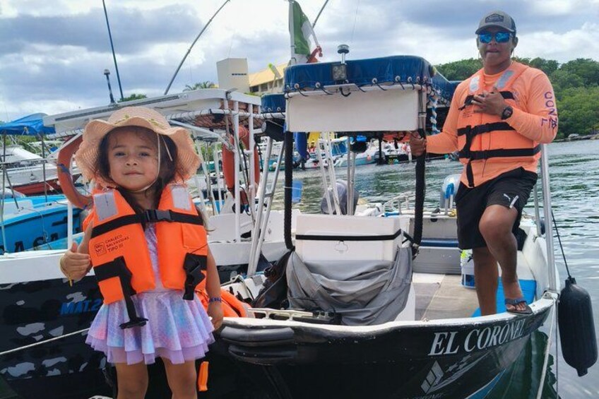 Una embarcación llamada 'EL CORONEL' con una persona y un niño, ambos con chalecos salvavidas. 5