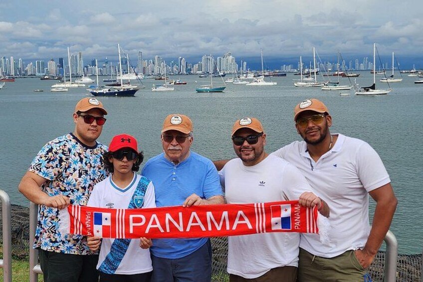 A group of people holding a Panama flag, with sailboats and a city skyline in the background. 4