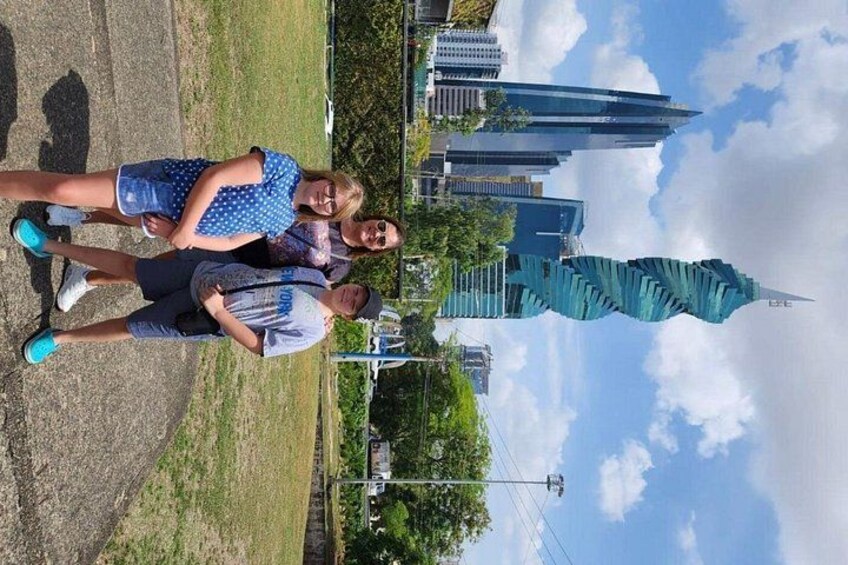 A group of people standing in a park with a modern building in the background. 3