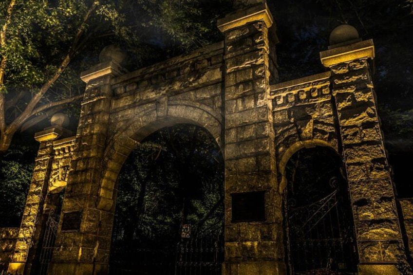 Un arco de piedra iluminado con detalles tallados, rodeado de árboles. 4