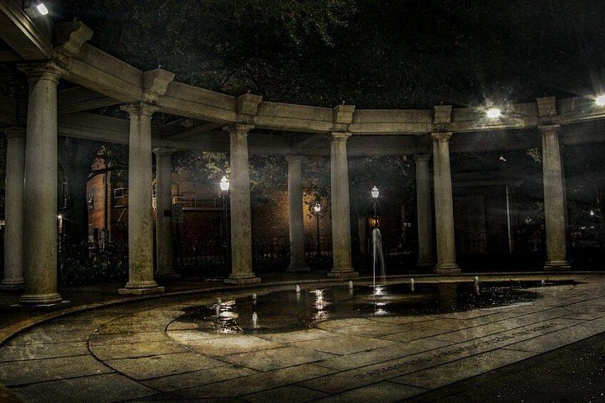 Escena nocturna con una fuente, columnas y un edificio al fondo. 5