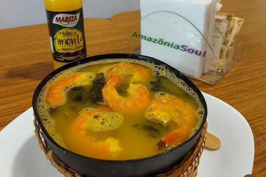 A bowl of soup with shrimp and vegetables, a bottle of Mariza, and a sign for AmazoniaSoul. 4