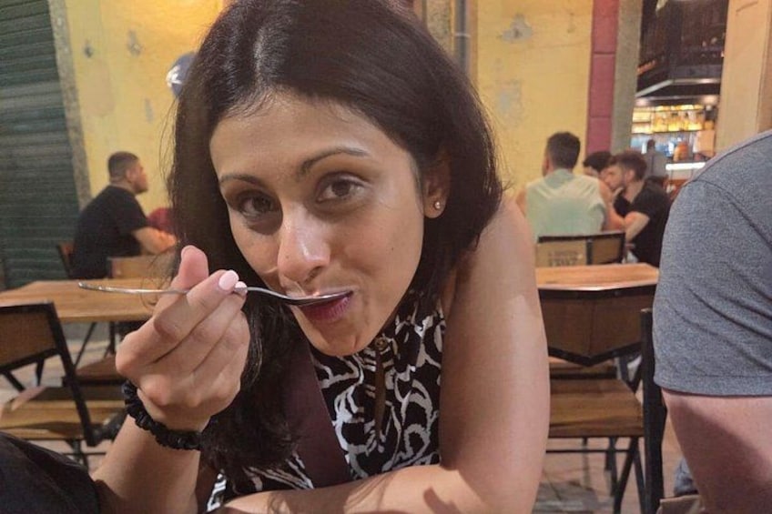 A person sitting at a table in a restaurant with other diners in the background. 2