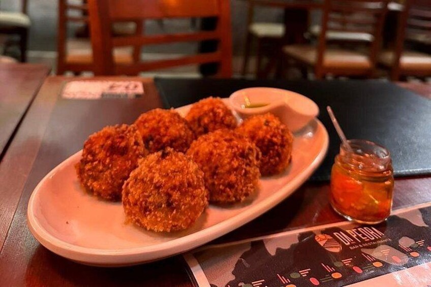 A plate of fried food with a dipping sauce and a small jar of sauce on a table. 3