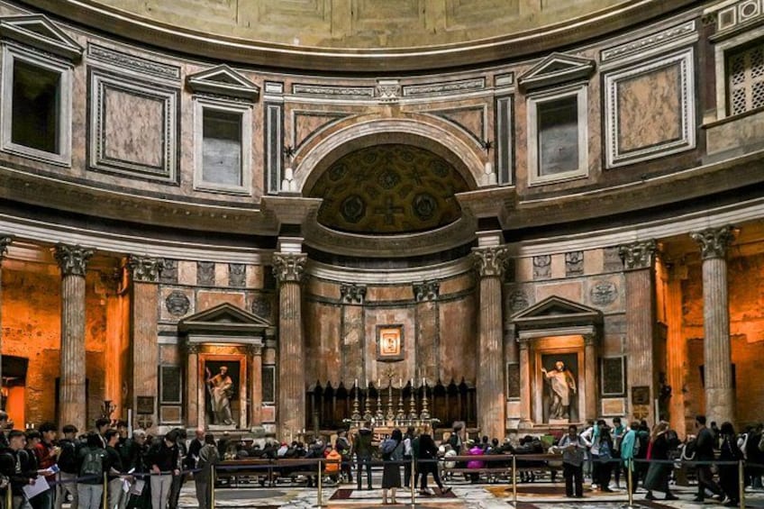 A grand hall with columns, a central altar, and a crowd of people. 1