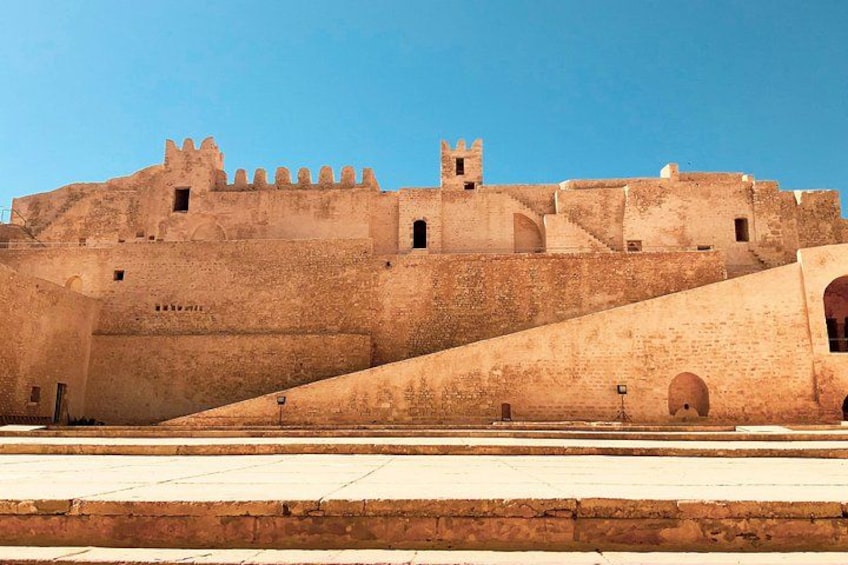 A historic fort with a large rampart, crenellations, and a clear blue sky. 5
