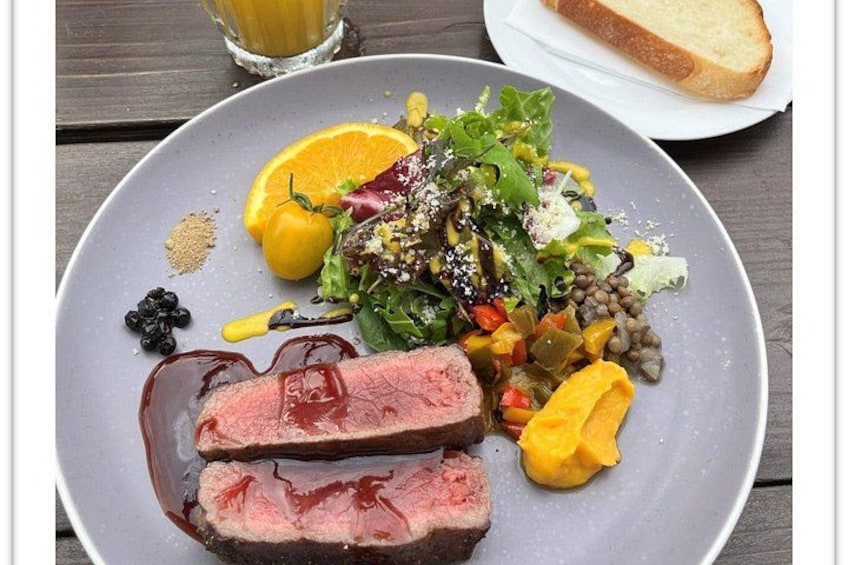 A plate of food with a slice of meat, vegetables, and a side of bread. 4