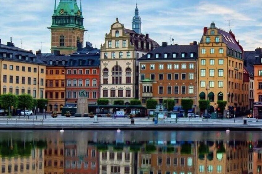 Ein Ufer mit historischen Gebäuden, einem Glockenturm und einem Spiegelbild im Wasser. 5