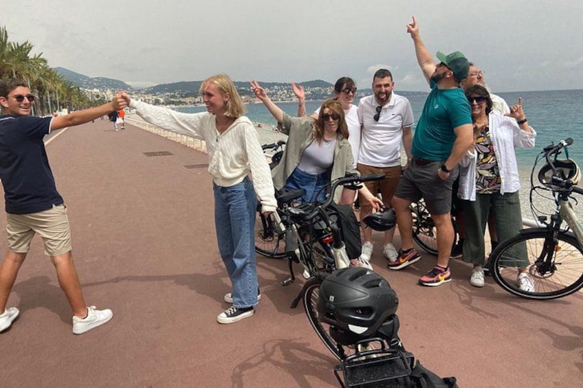 A group of people on a coastal promenade with bicycles and a scooter. 2