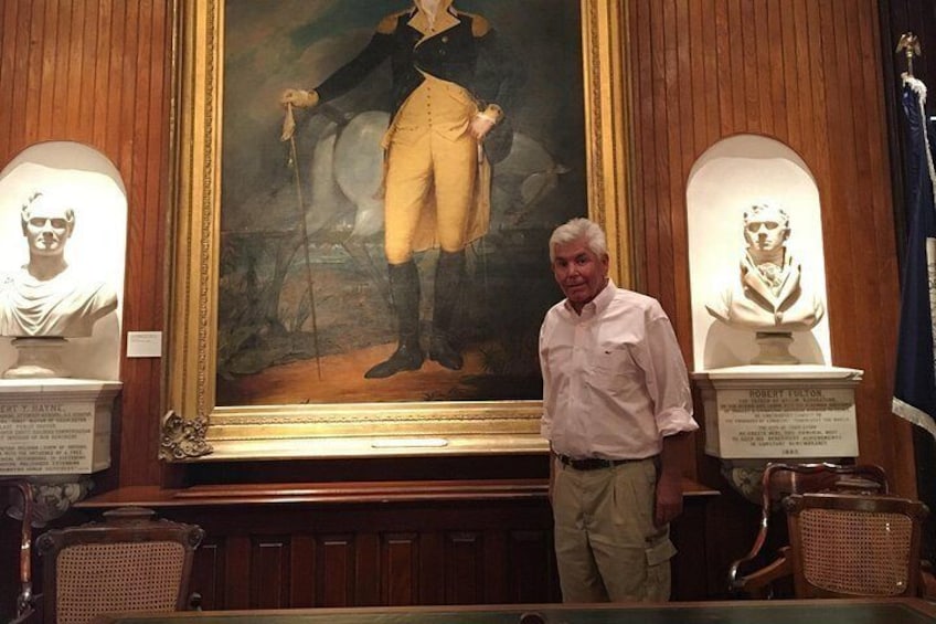 A man standing in front of a large painting with busts on either side. 5