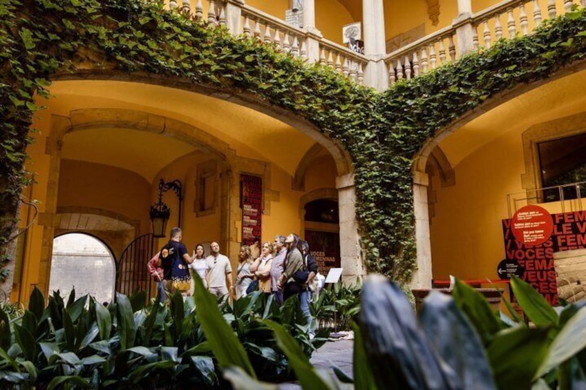An outdoor courtyard with arches, a group of people, and a banner. 5